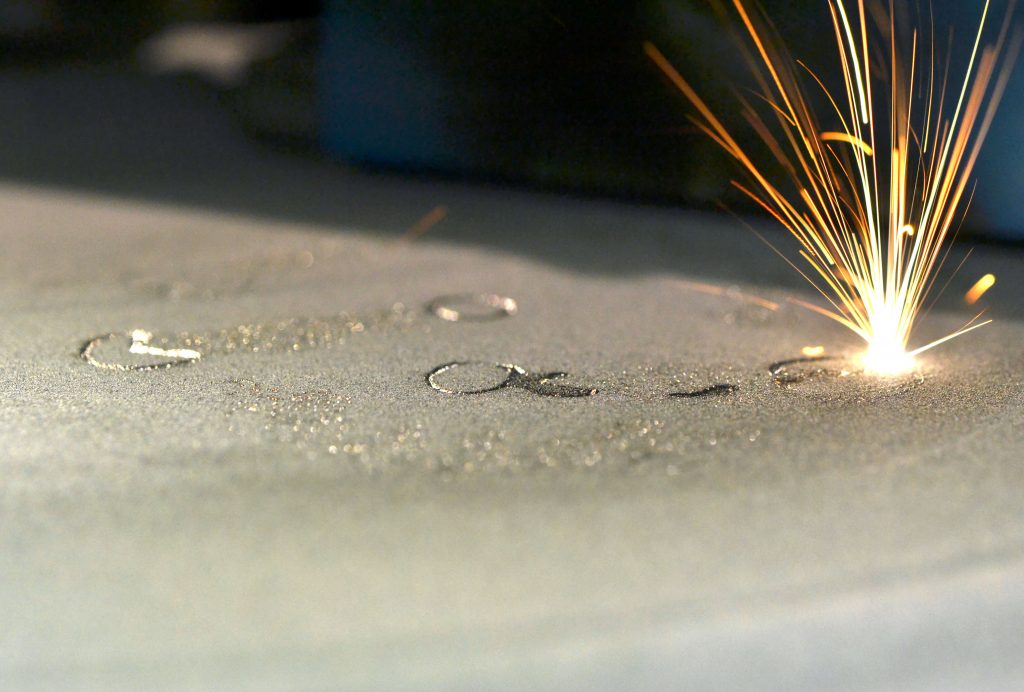 Powder Bed Fusion (PBF) using a laser to fuse a layer of metal material.